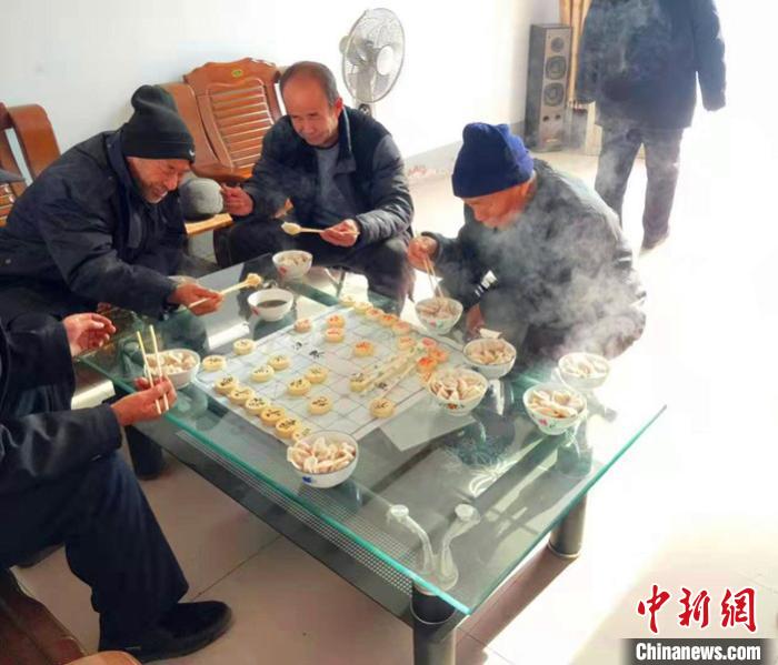 在平乡县柴口村的幸福小院里，老人在一边下棋一边吃饺子。　李铁锤 摄