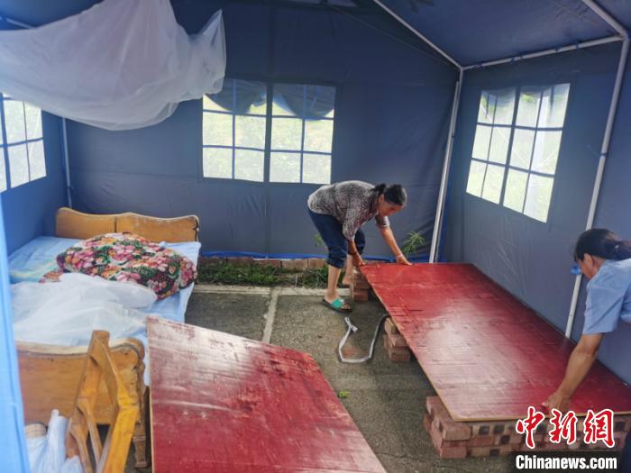 图为灾民在帐篷内铺设简易床铺 方安宁 摄 图为灾民在帐篷内铺设简易床铺 方安宁 摄